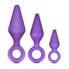 Three purple butt plugs, each with a tapered tip and slim neck. Each features a reinforced ring at the base for safety. This anal trainer kit features a small, medium, and large plug. Additional images show alternate angles.