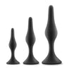 Set of three progressively sized black smooth silicone anal plugs, perfect for anal training. Each plug features a gently tapered tip, slight bulbous shape in the slim body, a narrower neck, and a circular flared base for safety.  Additional images show alternate angles.