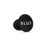 A smooth black bulbous butt plug with a tapered tip and the word "SLUT" printed on the base in white letters. Additional images show alternate angles.