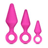Three pink butt plugs, each with a tapered tip and slim neck. Each features a reinforced ring at the base for safety. This anal trainer kit features a small, medium, and large plug. Additional images show alternate angles.